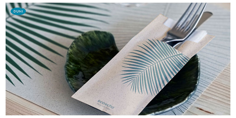 Elegante Tischdekoration mit grünen Bestecktaschen und gedecktem Besteck, stimmungsvolles Ambiente