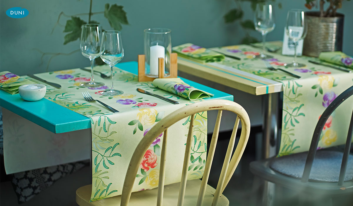 Tischläufer von Duni mit floralen, saisonalen Mustern, dekorativ auf gedeckter Tafel mit passenden Servietten und zarten Blütenakzenten