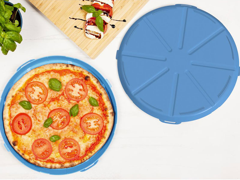 Ein Mehrweg Pizzateller, auf dem eine Pizza liegt, auf einem Tisch