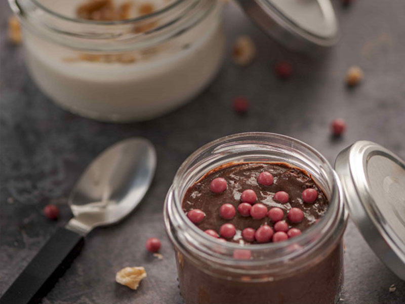 Zwei Desserts in Einmachgläsern auf einer Arbeitsplatte