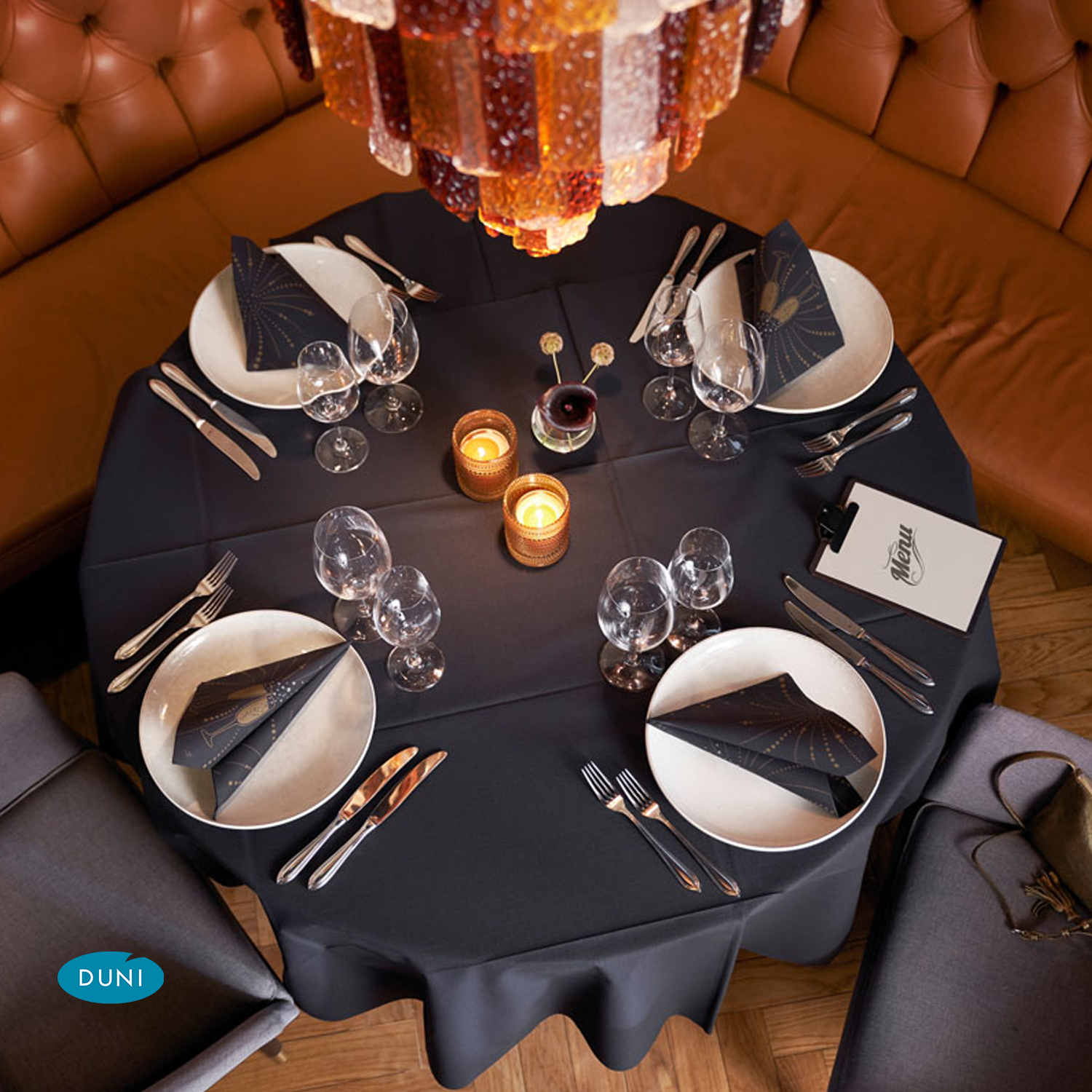 Ein runder gedeckter Tisch mit einer schwarzen Tischdecke und schwarz-goldenen Servietten