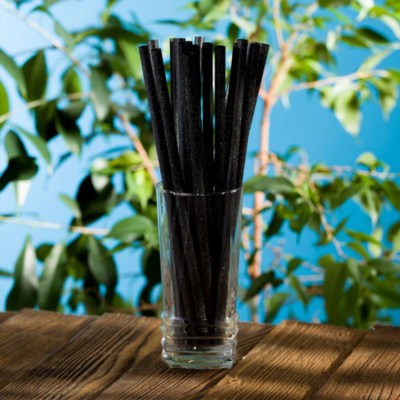 Trinkhalm aus Naturmaterialien, schwarz, im Cocktailglas auf einem Tisch