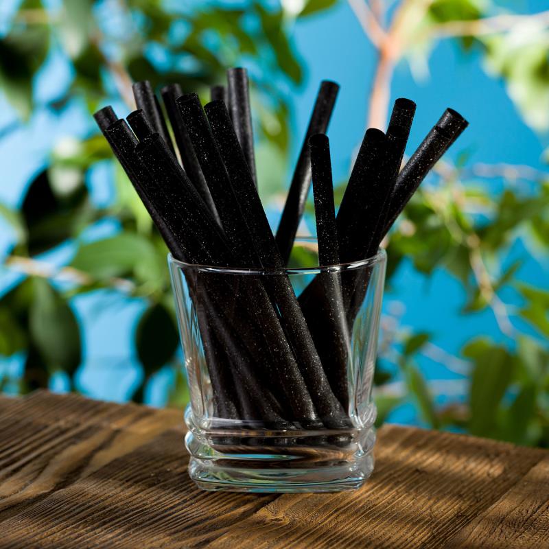 Trinkhalm aus Naturmaterialien, schwarz, im Cocktailglas auf einem Tisch